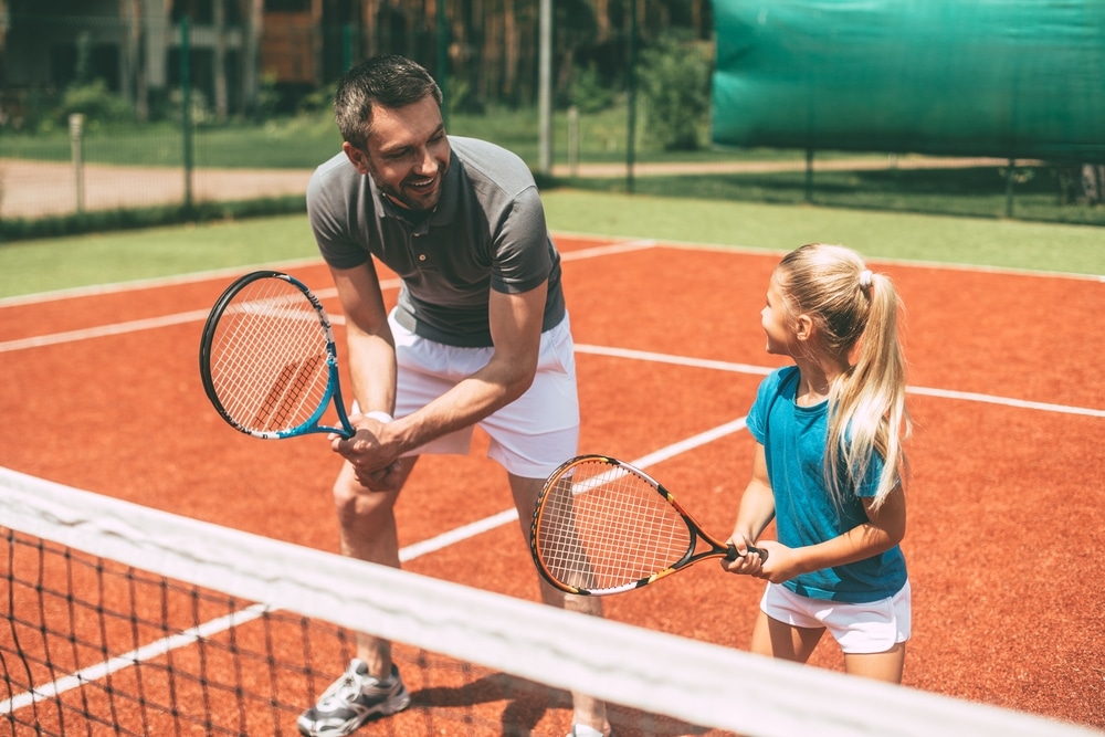 Father playing tennis with his daughter
