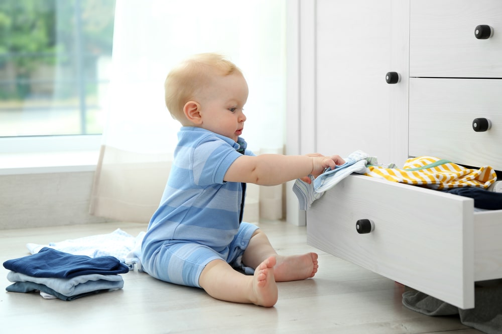 Baby putting clothes in a drawer