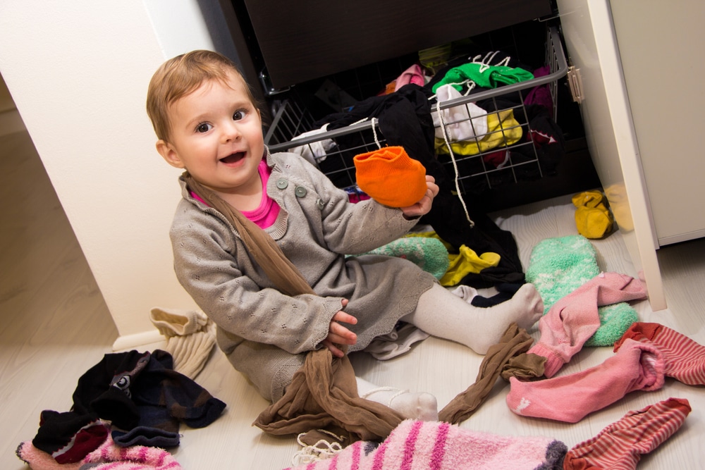Toddler sat on floor surrounded by clutter