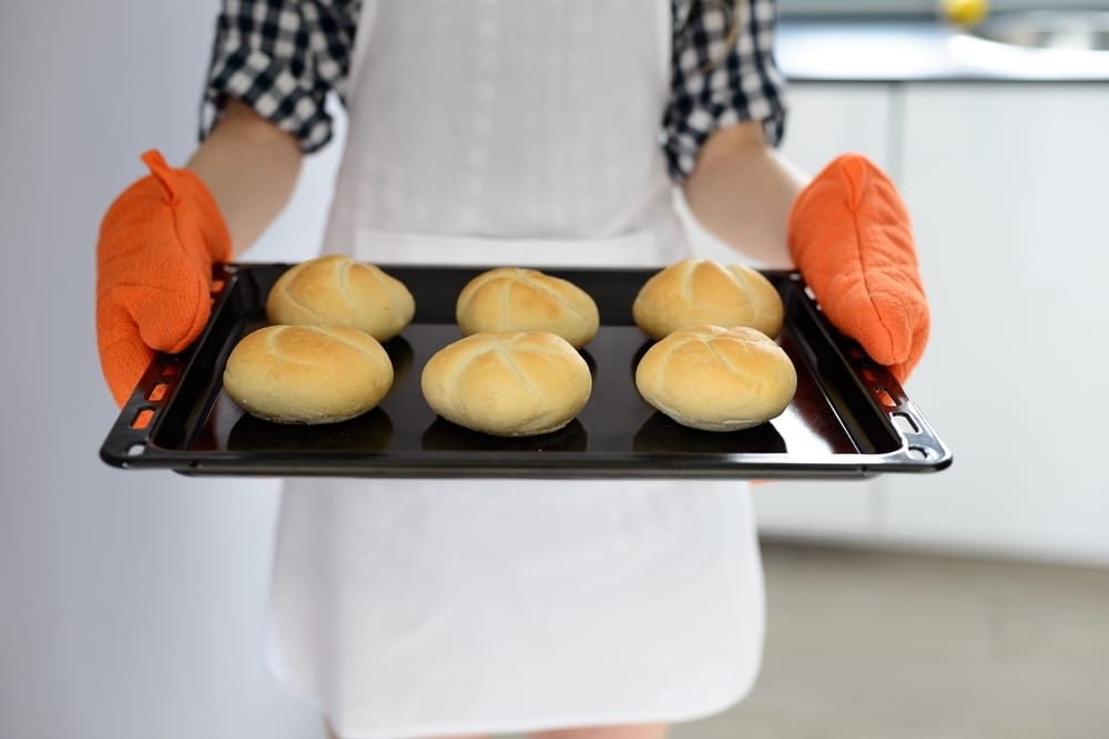 Student holding hot tray with oven gloves
