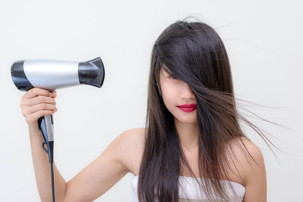 Young woman using hair dryer