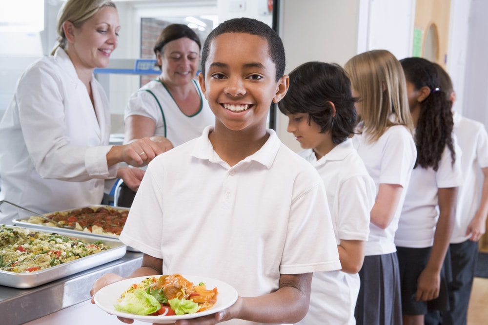 Young boy holding plate of school lunch