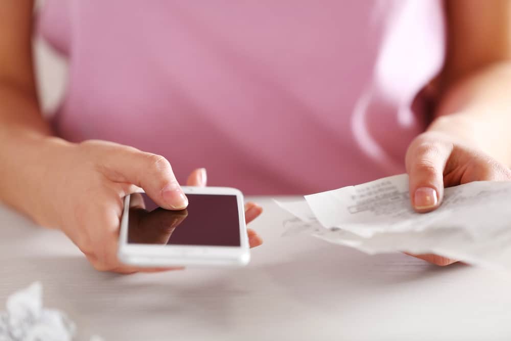 Woman looking at phone and receipts