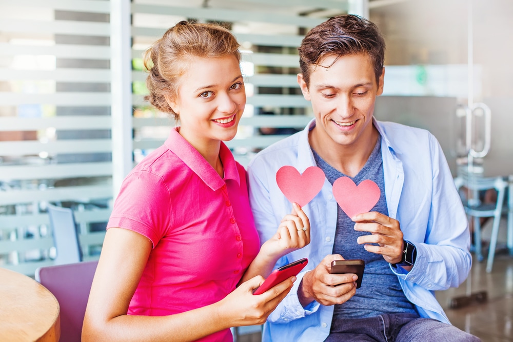 Man and woman holding phones and love hearts