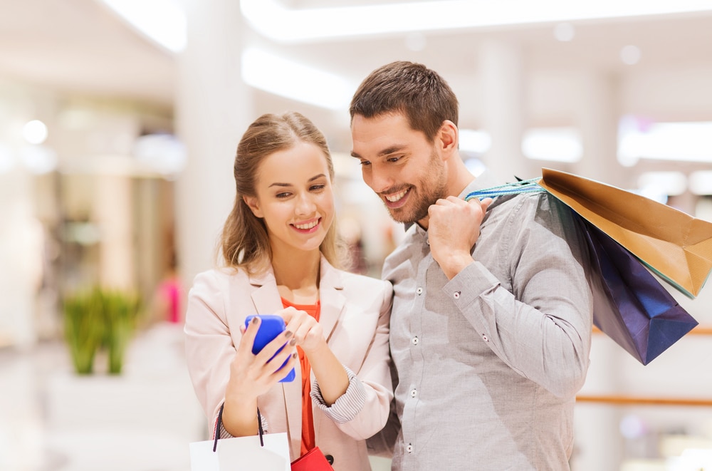 Young couple looking at a mobile while shopping