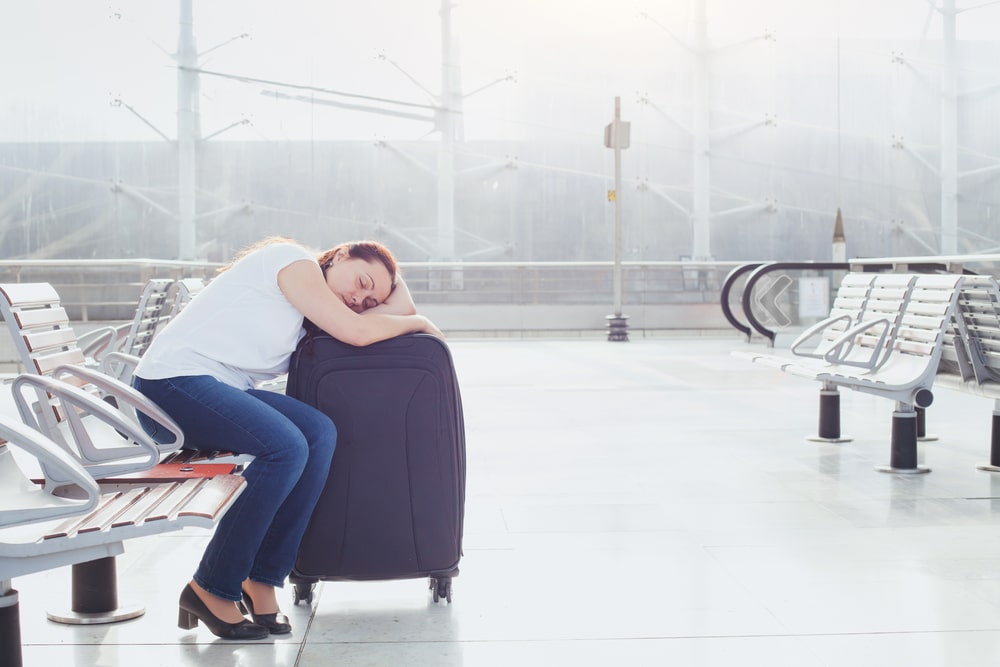 Woman sleeping on her suitcase at the Airport