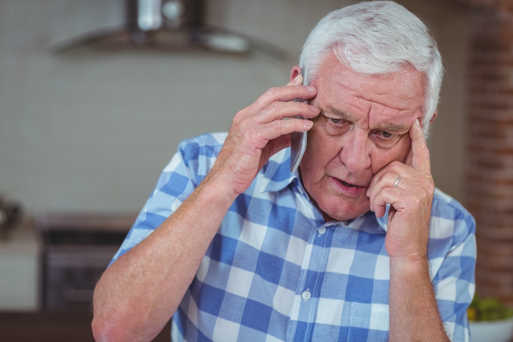 Worried elderly man making phone call