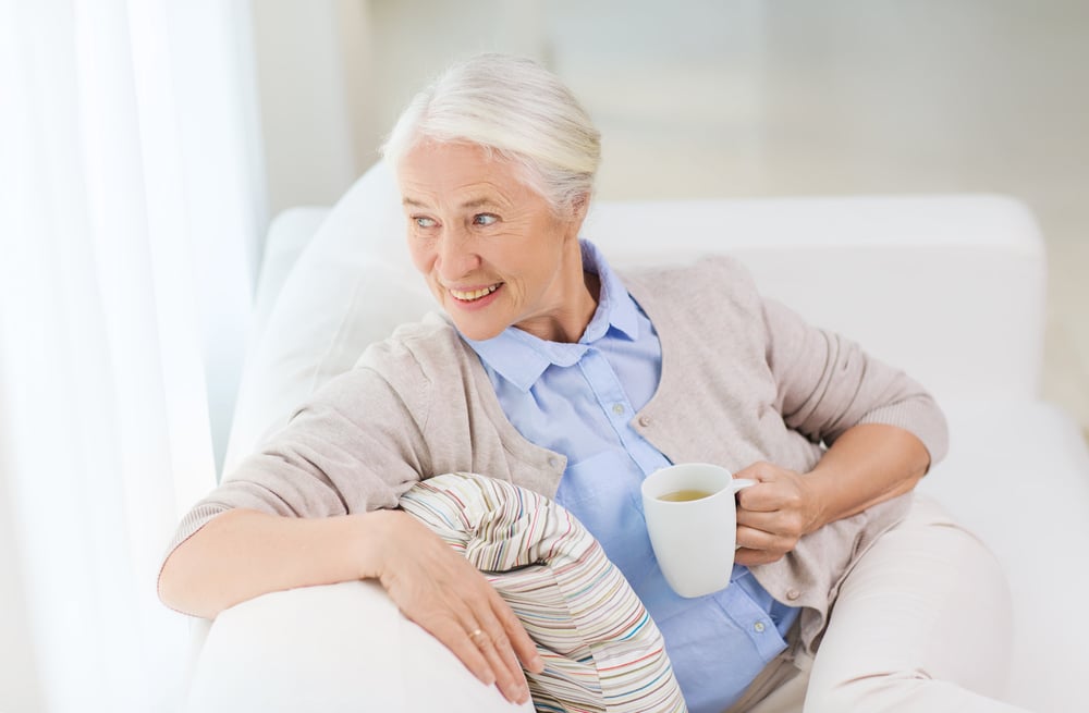 Elderly woman relaxes on the sofa with a cup of tea