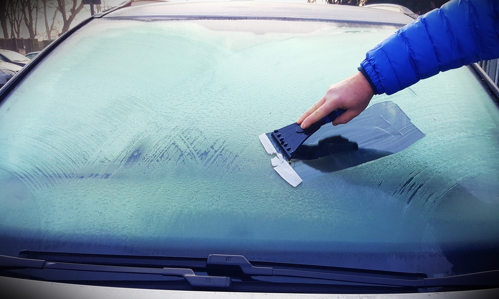 Man scraping ice off his car windscreen