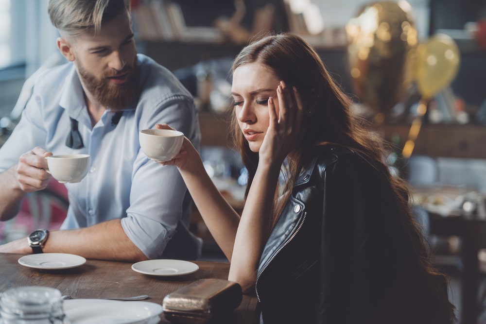 Man having coffee with hungover woman