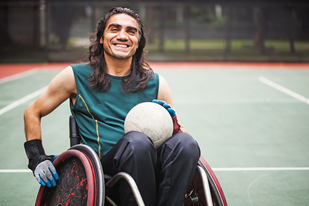 Happy wheelchair bound man playing basketball