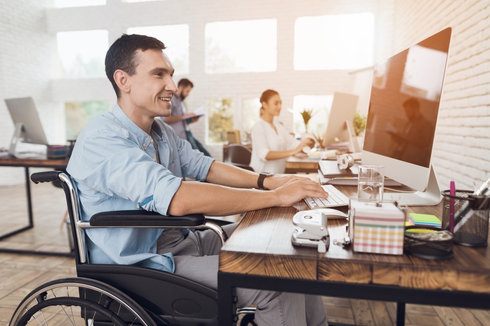 Happy Man in wheelchair working in an office