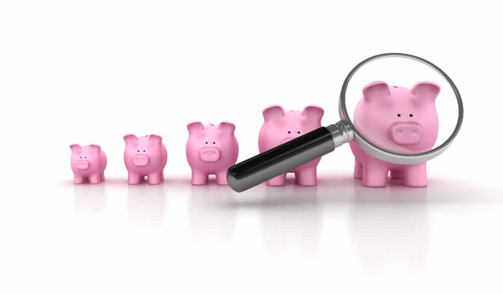Magnifying glass and different size piggy banks