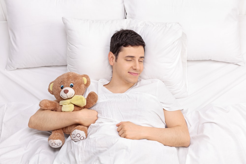 Man sleeping in bed with teddy bear