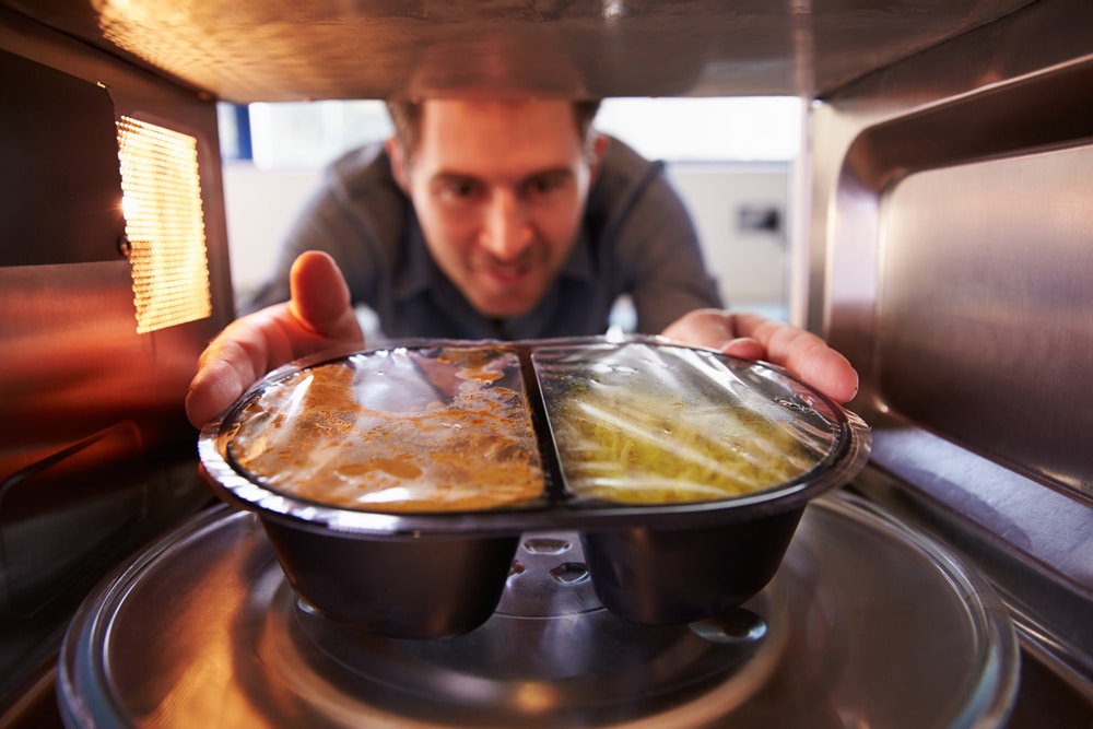 Man placing ready meal in microwave
