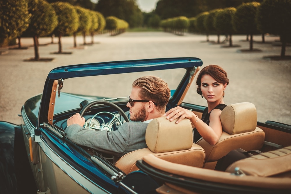 Wealthy couple in open top car