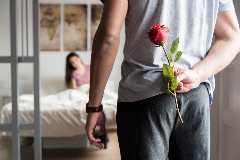 Single Red rose held behind mans back as a surprise for his girlfriend