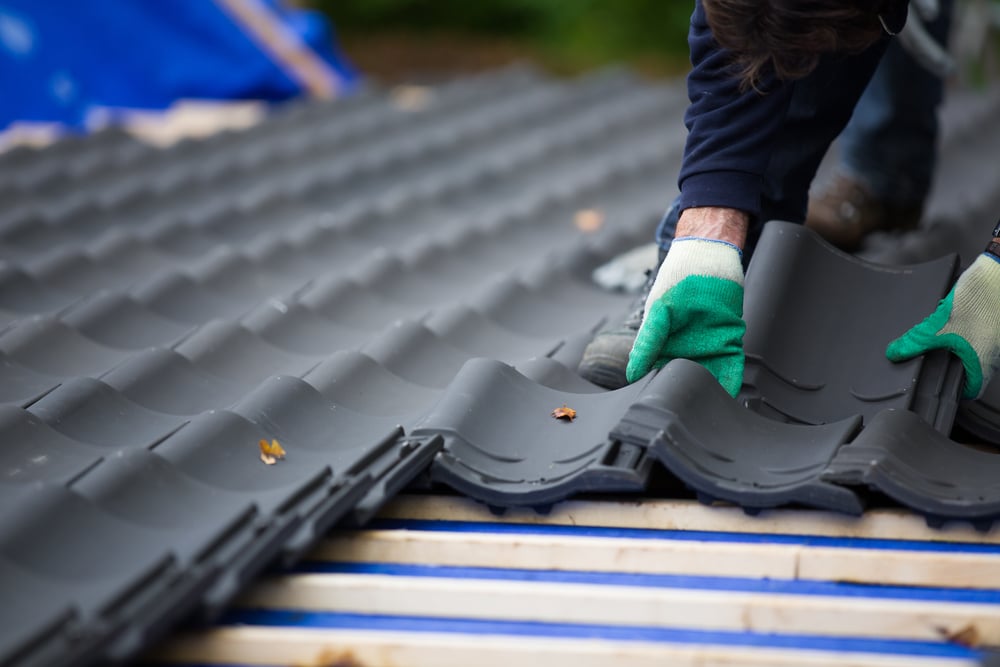 Builder laying roofing tiles