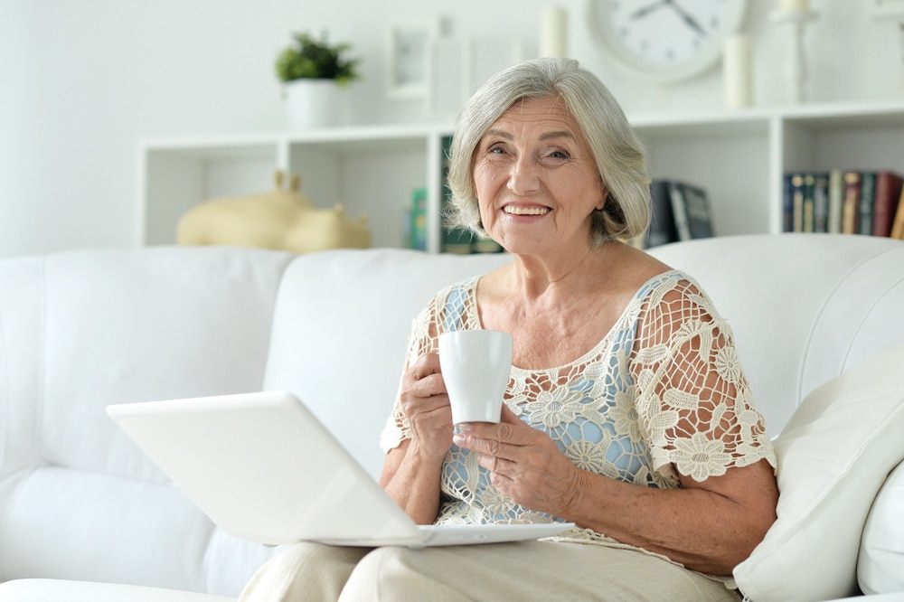 Senior woman sat in her living room with a laptop