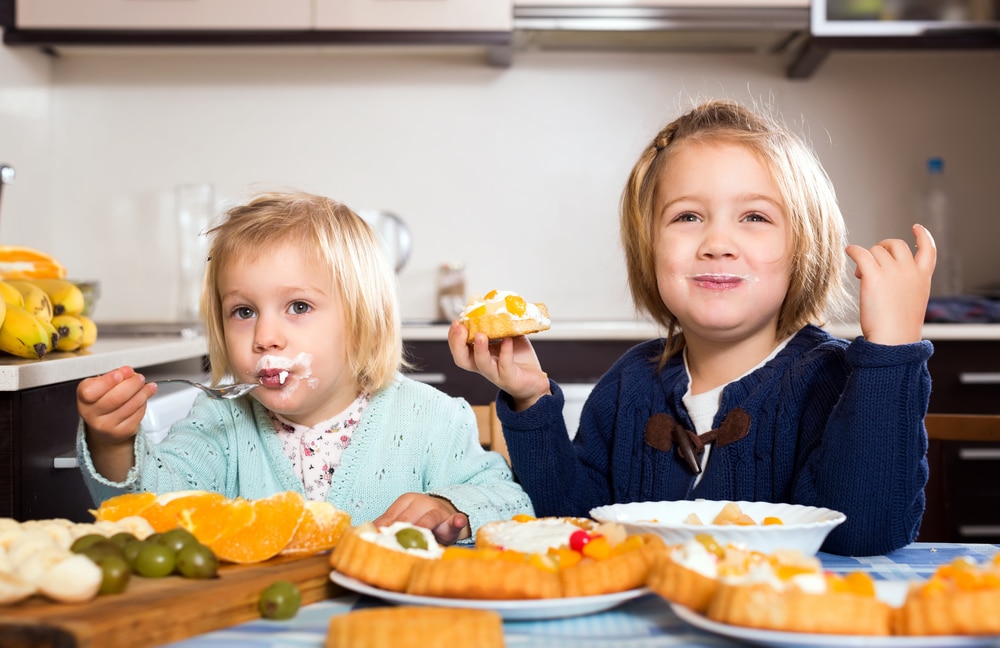 Little girls happily eating cakes