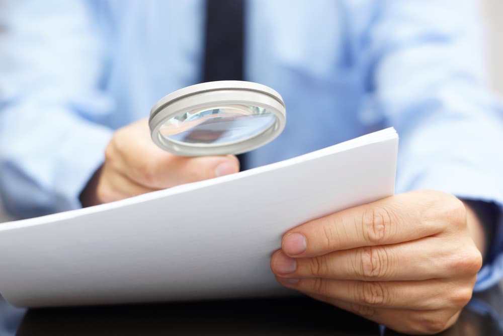 Man looking at small print on a document with a magnifying glass