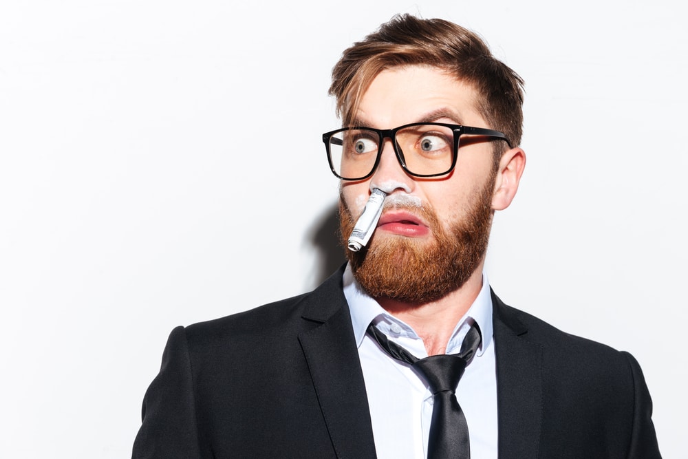 Shocked business man with rolled note and cocaine in his nose