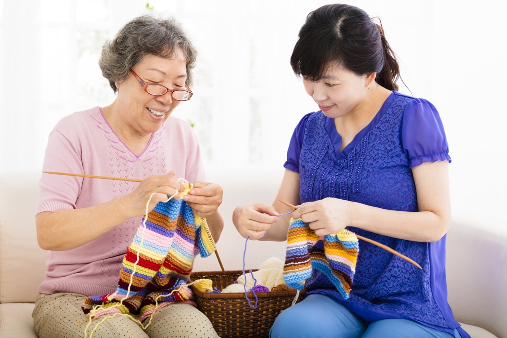 Older woman teaching younger woman to knit