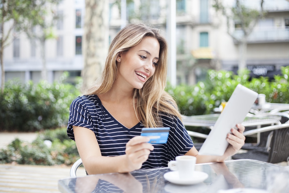 Happy woman holding credit card and tablet