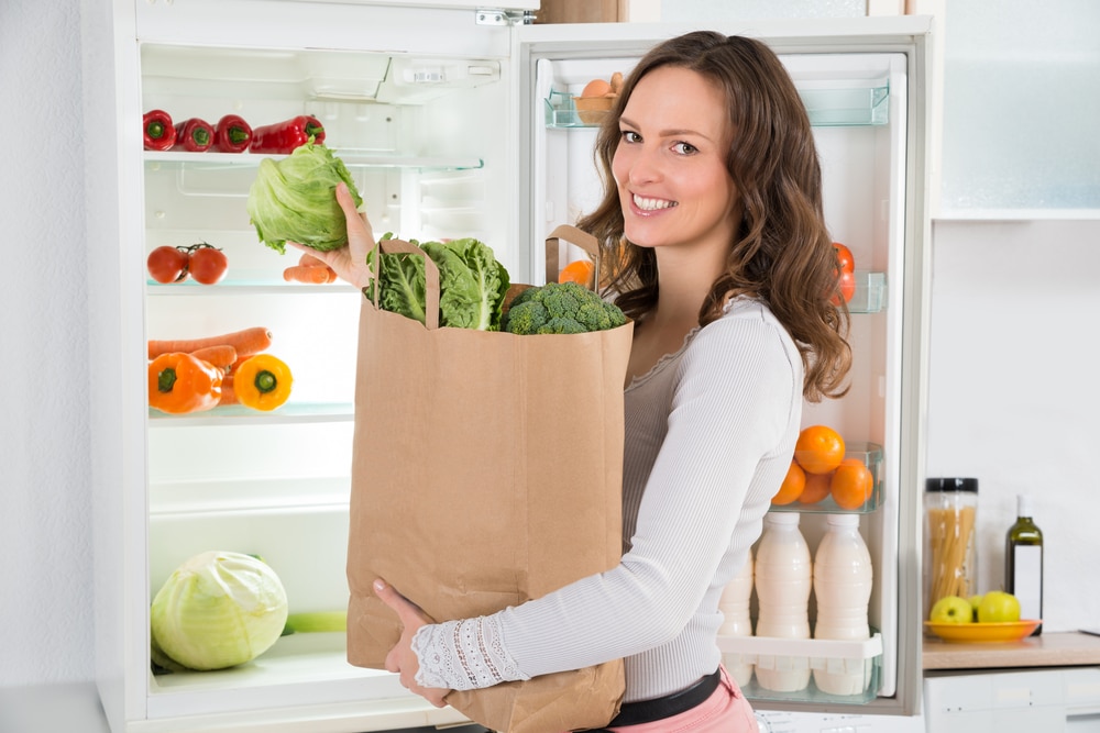 Woman putting groceries in the fridge