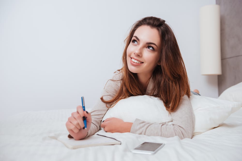 Woman writer lying on her bed looking thoughtful