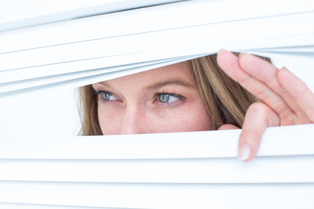 Woman spying through a window blind