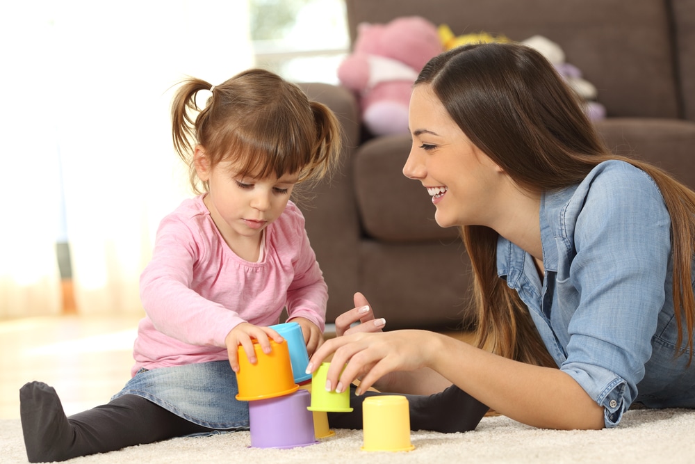 Young woman playing with toys with young girl