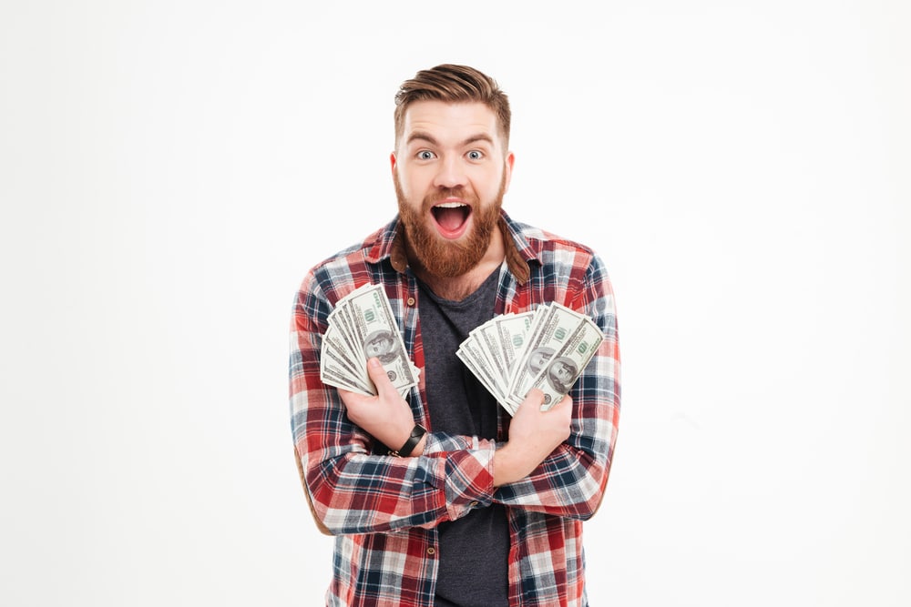 Excited male student holding handfuls of cash