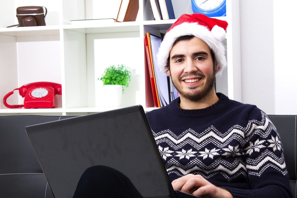 Young man in santa hat using laptop