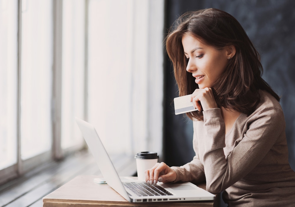 Young woman holding a credit card and using a laptop to shop online