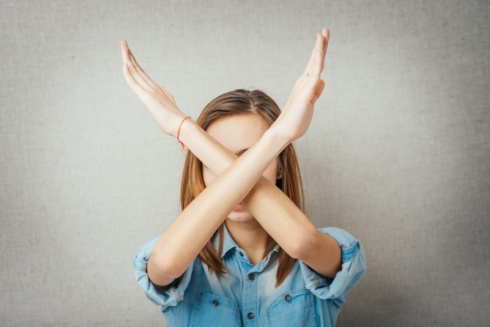 Woman holding arms up in an X sign to signify no