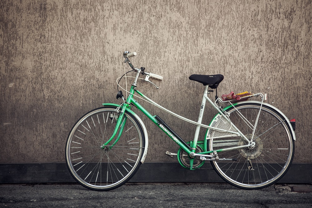 Green bicycle leaning against a wall