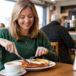 Woman enjoying an affordable cooked breakfast in a British caf&eacute;